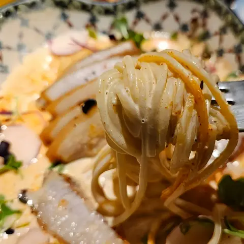 Creamy noodles twirled on a fork with pork slices