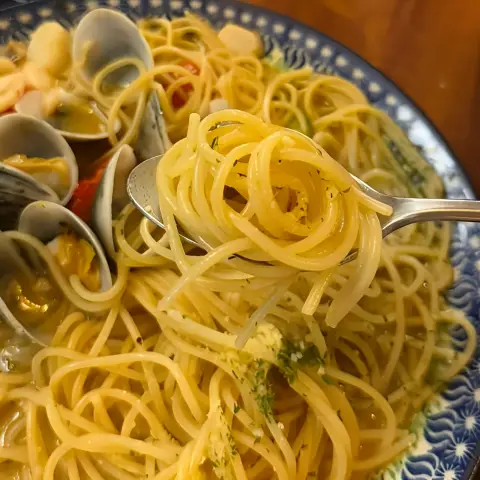 Al dente pasta swirl with vongole broth on a spoon
