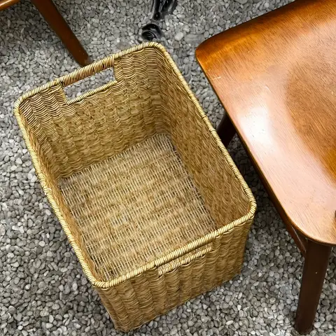 Woven basket for belongings placed beside a wooden chair