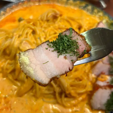 Thick slice of pork belly from rosé pasta dish