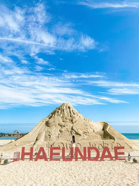 Visit Busan in 2025 – Sand sculpture and Haeundae sign at Haeundae Beach during the Sand Festival
