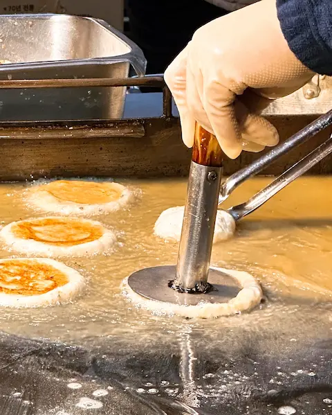 Street vendor frying seed-stuffed hotteok at a traditional market in Busan
