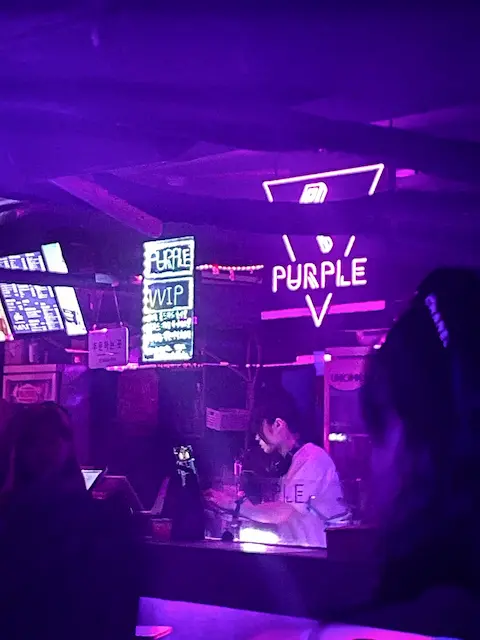 Bartender mixing drinks under neon lights at Hongdae club Purple