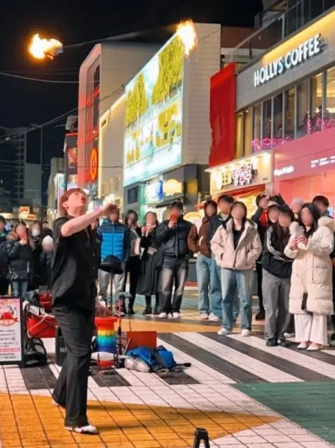 Fire juggler performing on a lively night street in Seoul
