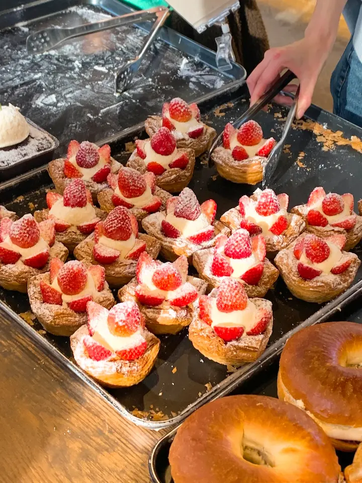 Dozens of strawberry pastries with whipped cream neatly arranged in a tray
