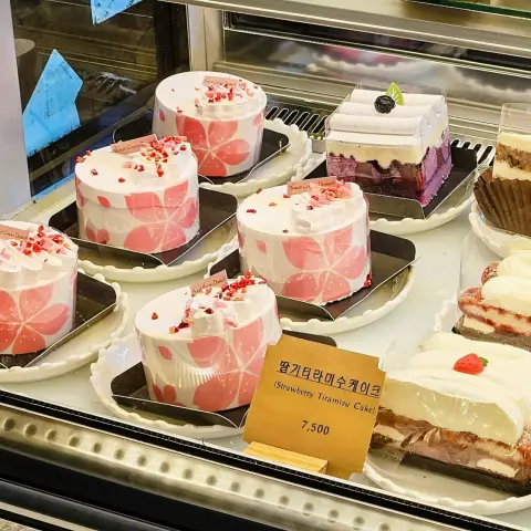 Strawberry tiramisu cakes and other slices arranged in a chilled display case