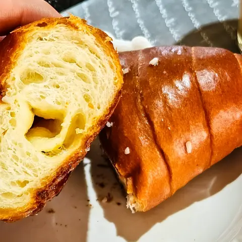 Salt bread with flaky layers and glossy crust torn open