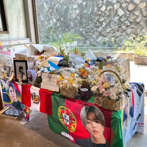 ZM illennial fan tribute table with flowers, notes, and international flags