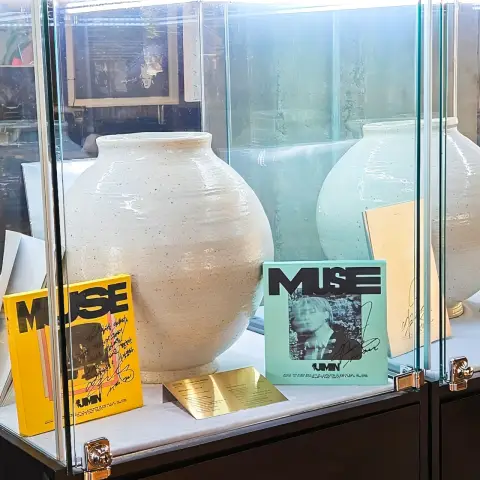 ZM illennial glass display with white ceramic jars and signed albums