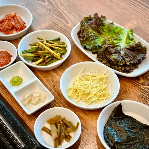 Side dishes at Ilpyeon Jangeo Hongdae including kimchi, ginger, and greens