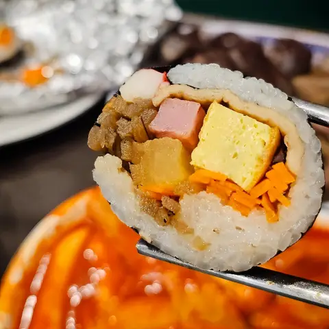 Close-up of gimbap cross-section held with chopsticks