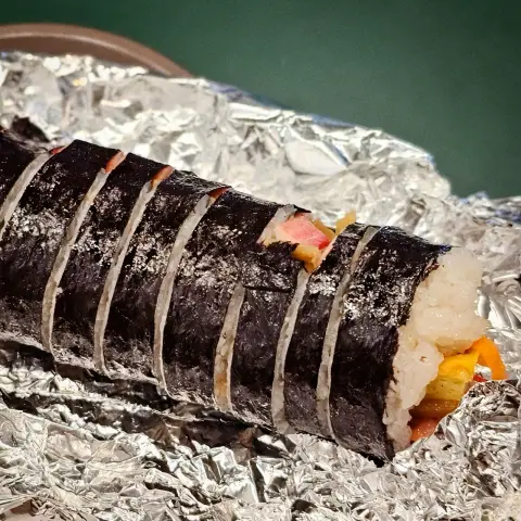 Whole gimbap roll wrapped in foil and cut into bite-sized pieces