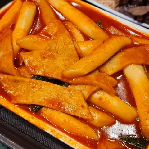 Tteokbokki and fish cake swimming in spicy-sweet red sauce