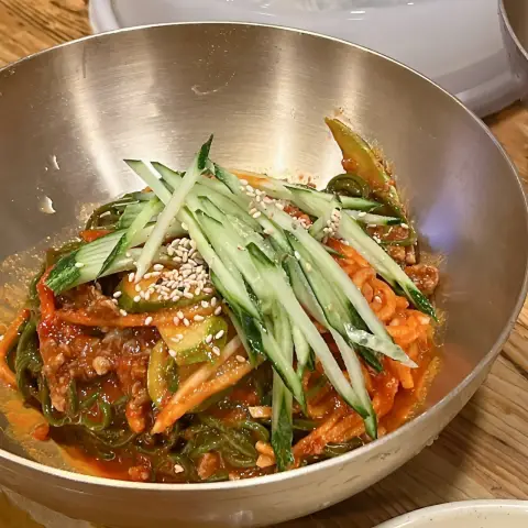 Bowl of bibim guksu topped with cucumber and sesame seeds