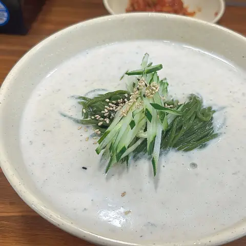 Full bowl of kongguksu topped with cucumber and sesame seeds