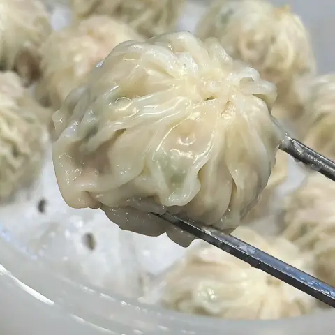 Steamed dumpling held with chopsticks at Myeongdong Kyoja