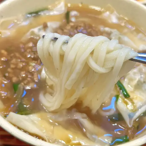 Spoon lifting Myeongdong Kyoja’s hand-cut noodles from the broth