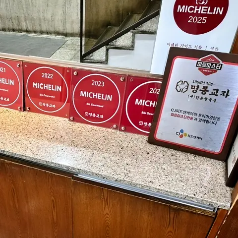 Michelin Bib Gourmand plaques displayed inside Myeongdong Kyoja