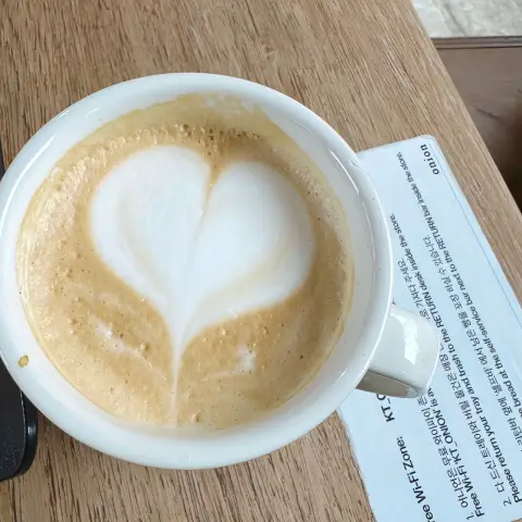 Heart-shaped latte art in a ceramic cup on wooden table