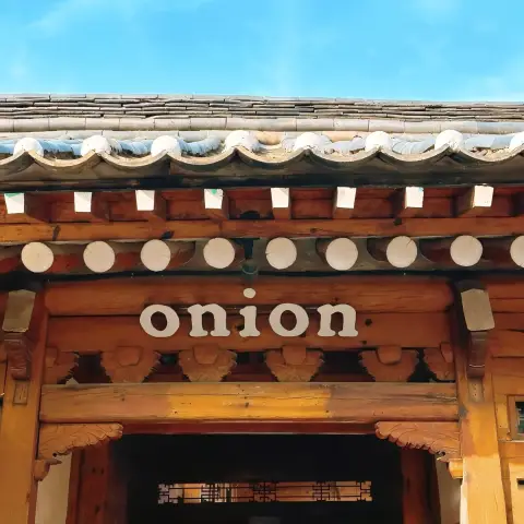 Cafe onion anguk menu inside begins here—under the wooden hanok gate with the iconic sign