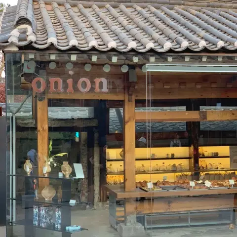 Wood-framed glass facade of Cafe Onion Anguk with pastries visible inside