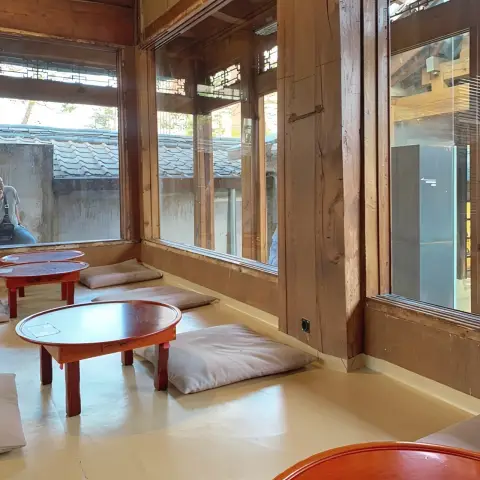 Traditional floor seating at Cafe Onion Anguk with red round tables and gray cushions