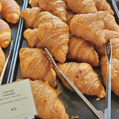 Golden croissants from the cafe onion anguk menu lined up on a black tray