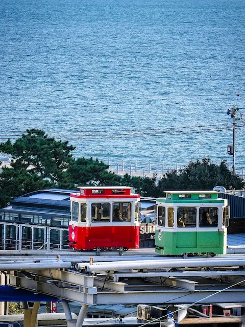 Red and green sky capsules running along the Haeundae Blueline Park monorail