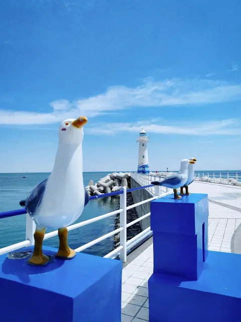 Cheongsapo lighthouse and seagull sculpture under a clear blue sky