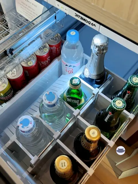 Mini fridge at Park Hyatt Busan fully stocked with Perrier, soda, and champagne