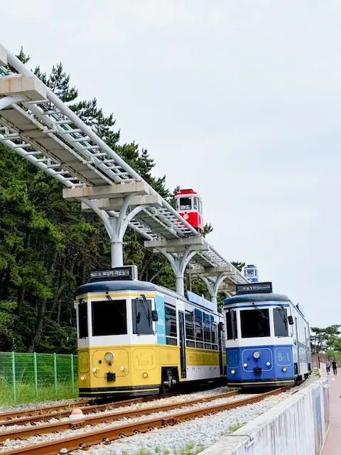 Beach train and sky capsule pass each other along the Haeundae Blueline Park route