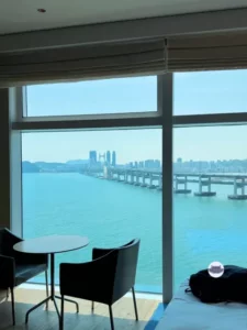 Room with round table and ocean-facing windows overlooking Gwangan Bridge