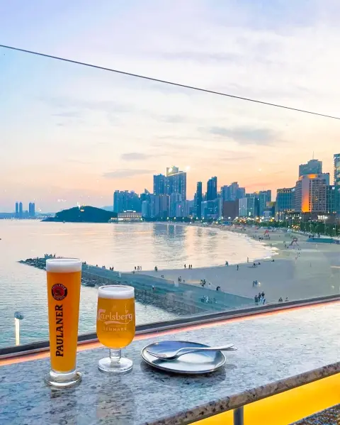 haeundae-bar-skyline-view-with-beer.webp Evening skyline view from Haeundae bar with Paulaner and Carlsberg