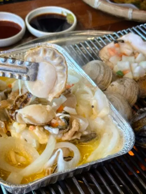 Grilled shellfish platter in butter broth at a Cheongsapo restaurant