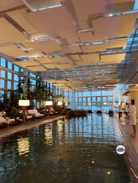 Indoor swimming pool at Park Hyatt Busan with lounge chairs and full-length windows