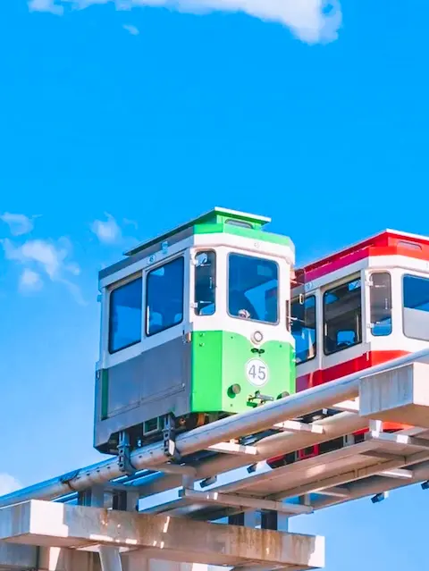 Green and red capsule crossing the sky rail with blue skies above