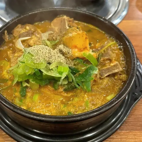 Spicy gamjatang bubbling with pork bones and fresh green onions at Boseong Hoegwan