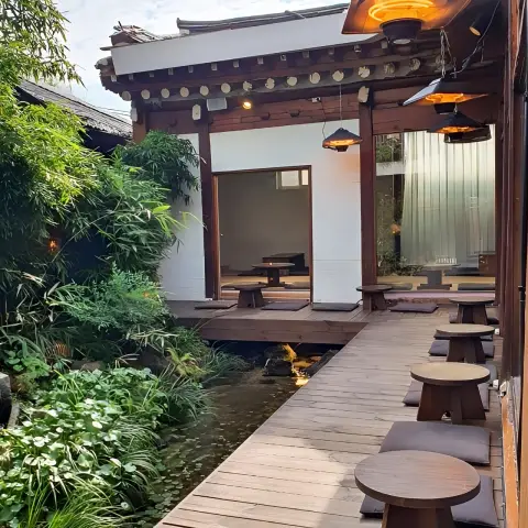 wooden deck with round tables connecting hanok rooms over a pond