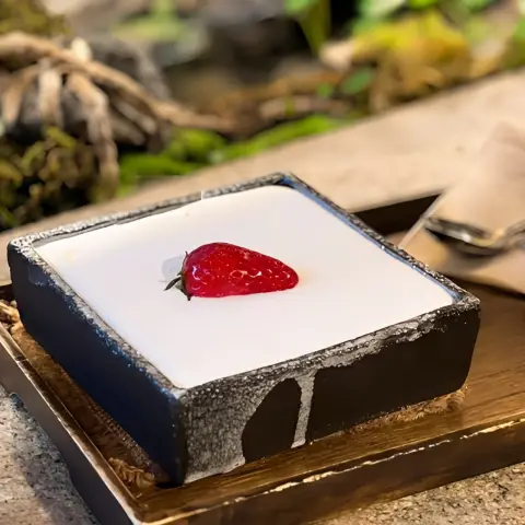 square strawberry cake topped with whipped cream and a single strawberry