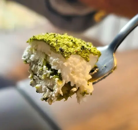 spoonful of matcha cream dessert with layers of green tea and whipped topping