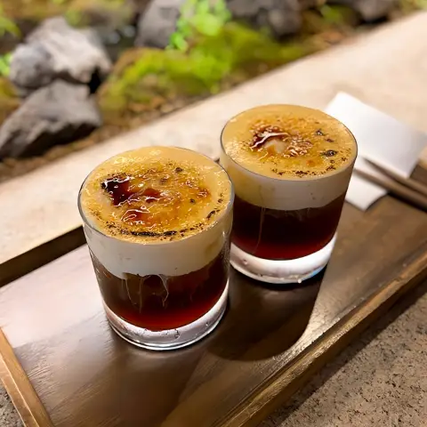 two glasses of torched cream egg coffee on a wooden tray