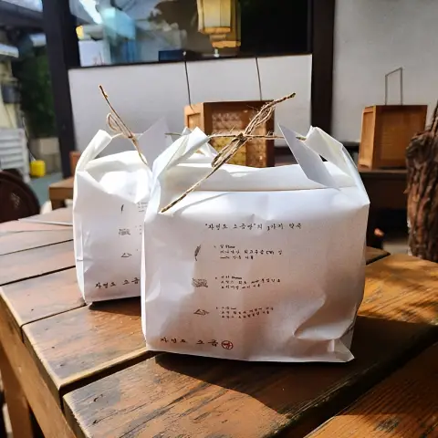 Two takeaway bags from Jayeondo Salt Bread resting on a courtyard table