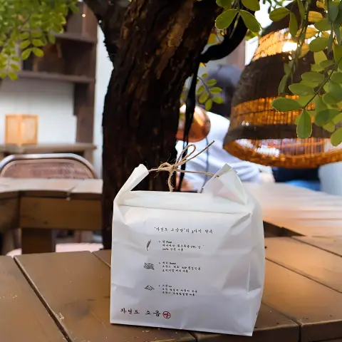 Paper bag from Jayeondo Salt Bread under a tree in the courtyard