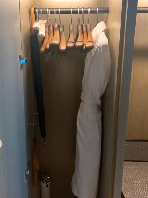 Closet at Signiel Busan with hangers, umbrella, and bathrobe