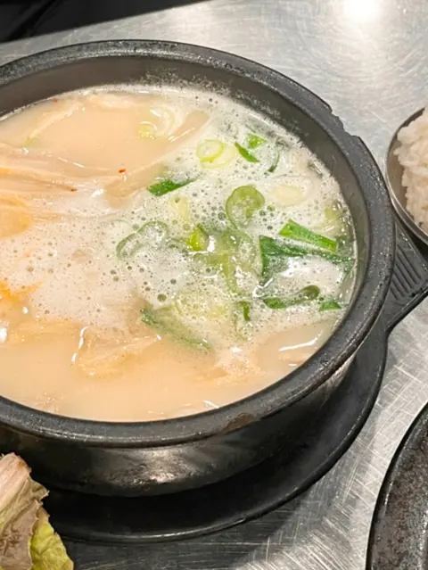 Steaming pork broth with scallions and rice bowl on the side