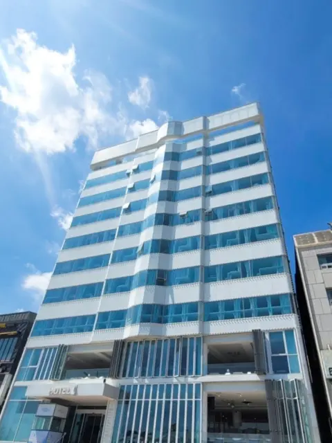 gwangalli-hotel1-building-day.webp Exterior of gwangalli hotel 1 building with modern glass facade under blue sky