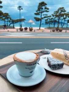 A cozy morning at Casa Busano Gwangan with coffee, brownie, and a sea view across Gwangalli Beach.