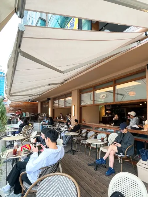 Outdoor seating at Casa Busano Gwangan offers a lively atmosphere with a direct ocean breeze and a great spot for people-watching.