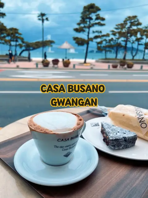 A signature shot of Casa Busano Gwangan with coffee and dessert in the foreground and the beach as the backdrop—Instagram-ready.
