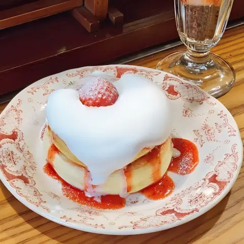 Fluffy souffle pancake topped with whipped cream and a single strawberry